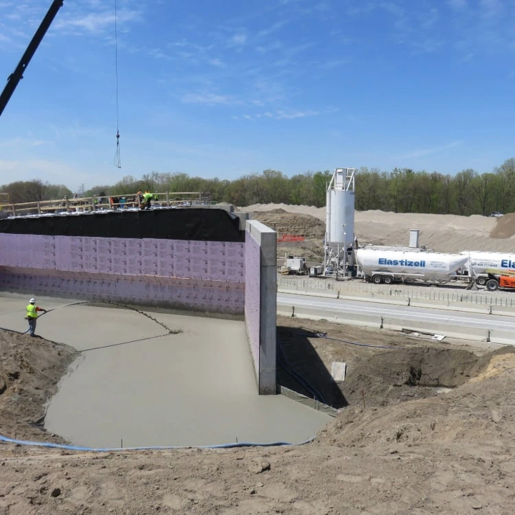 Elastizell Systems applying lightweight cellular concrete to stabilize a retaining wall during construction